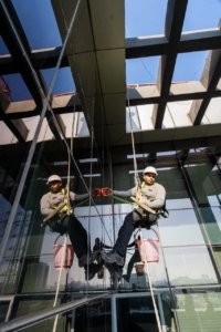 Rope access workers cleaning the windows of a tall glass building