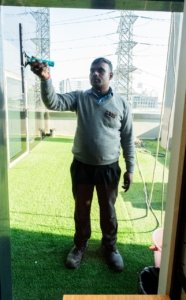 CAS Facilities team member cleaning an exterior glass wall on a rooftop area using a window squeegee.